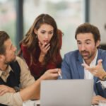 Zespół analizujący coś wspólnie na ekranie laptopa w biurze