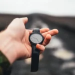 Dłoń trzymająca zegarek na tle drogi, koszt dnia opóźnienia wydania oprogramowania