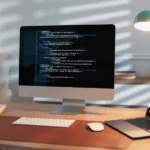 Biurko z monitorem i kodem, testy manualne kontra automatyzacja testów w małej firmie