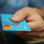 Dłoń trzymająca niebieską kartę płatniczą, Black Friday jako test odporności systemu i checkoutu