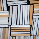 Gęsto ułożone książki widziane od strony grzbietów i kartek, lektury zmieniające myślenie o pracy w IT