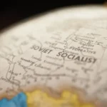 Zbliżenie globusa z mapą świata, mapa dojrzałości QA i pięć poziomów rozwoju jakości