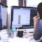 Osoba przy biurku z dwoma monitorami w małym zespole, jak startupy testują bez dedykowanego QA