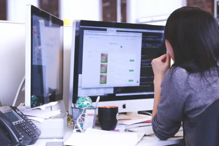 Osoba przy biurku z dwoma monitorami w małym zespole, jak startupy testują bez dedykowanego QA