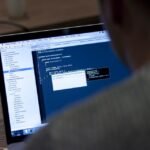 Ekran laptopa z kodem podczas pracy zespołu testerskiego nad jakością oprogramowania