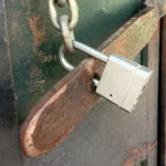 Metalowa kłódka na łańcuchu zabezpieczająca stare metalowe drzwi, testy bezpieczeństwa aplikacji