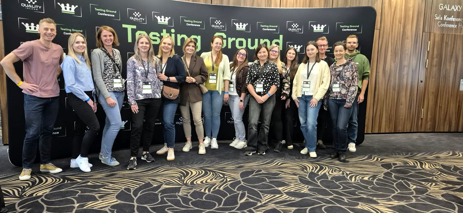 Pamiątkowe zdjęcie grupy uczestników przy ściance Testing Ground Conference 2026