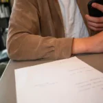 Osoba podpisuje dokument umowy ramowej na testy oprogramowania przy biurku
